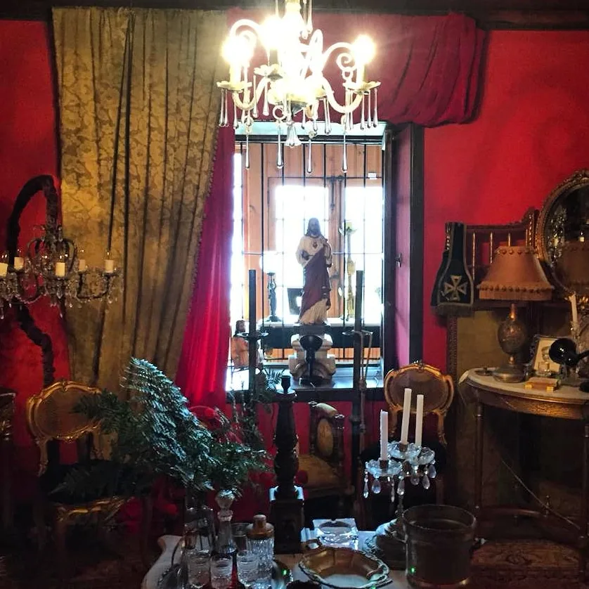 Pasillo interior de A Hotel Boutique Pelluhue con cortinas rojas, cuadros dorados y lámparas encendidas