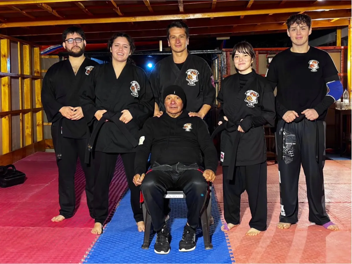 Instructores y equipo de la academia en el dojo, sobre tatami rojo y azul