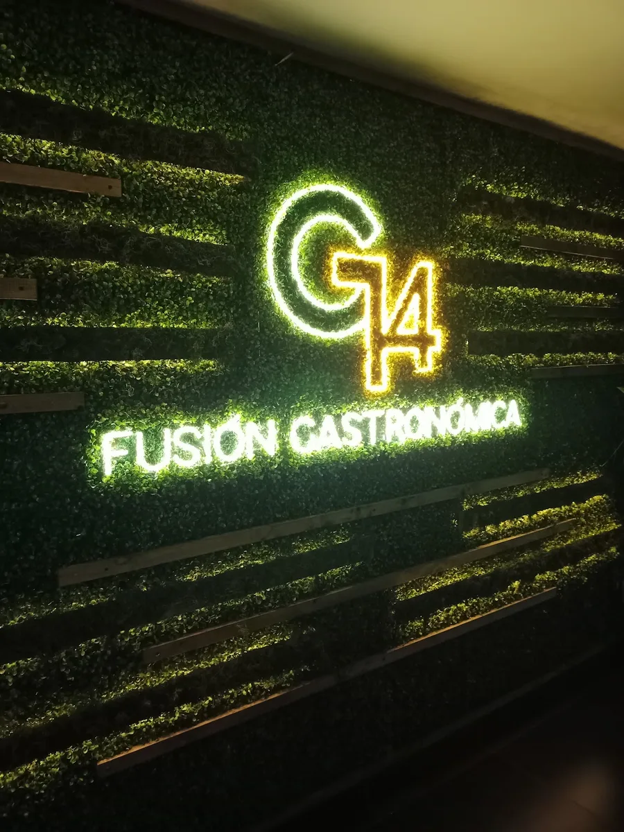Letrero de neón lima G14 Fusión Gastronómica sobre la pared de pasto del restaurante