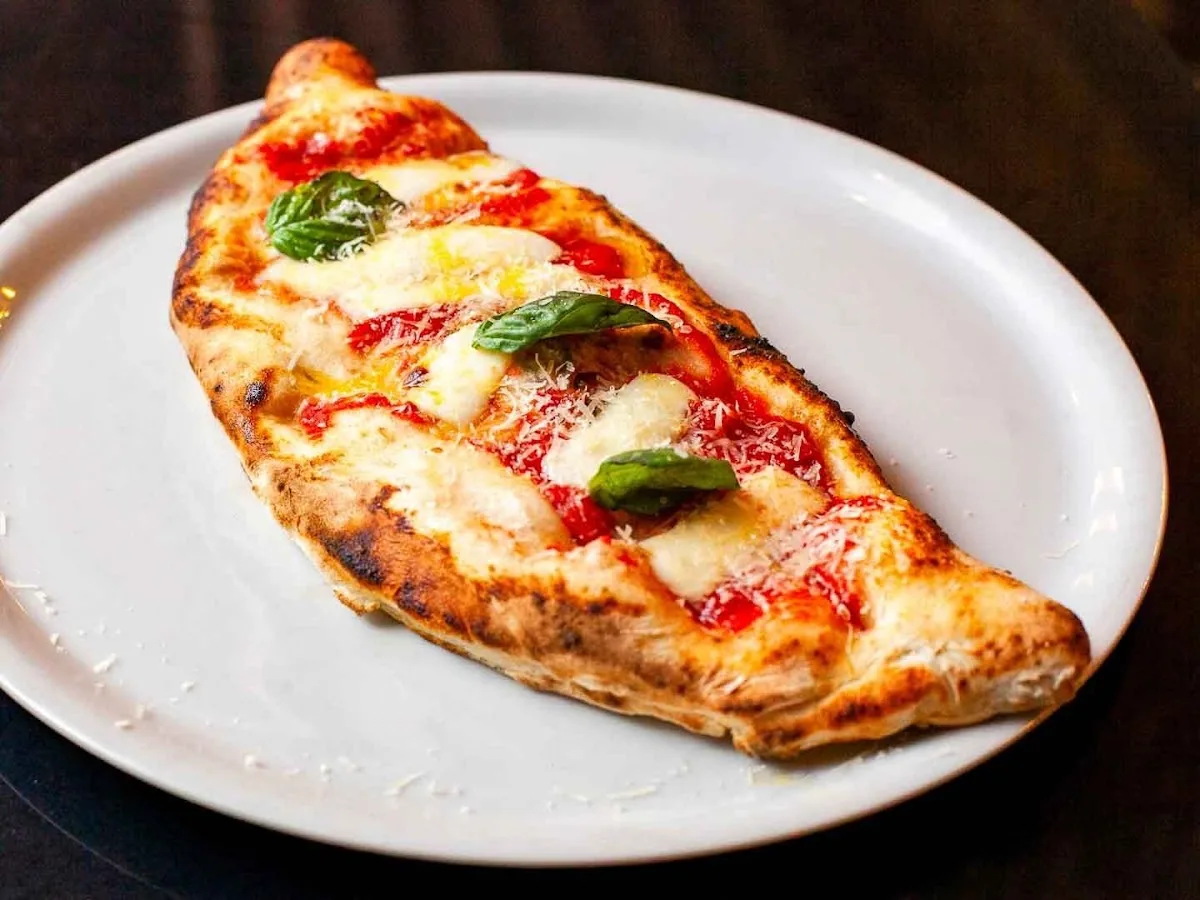 Calzone dorado servido sobre plato blanco