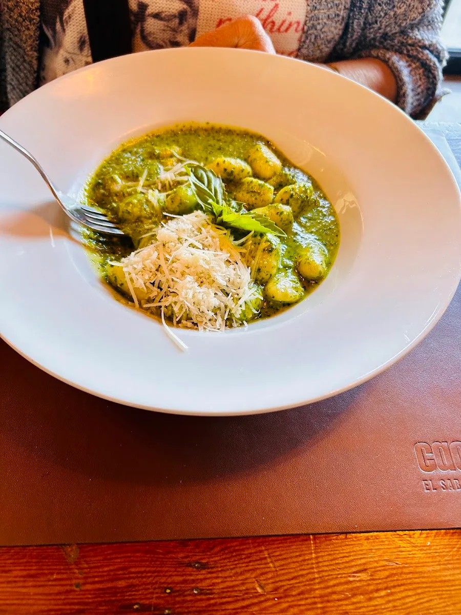 Ñoquis en salsa pesto verde servidos en plato blanco