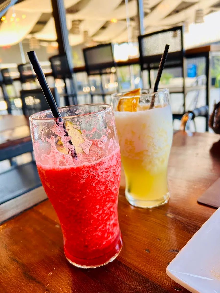 Dos tragos de colores sobre mesa de madera en la barra de Alma restaurant