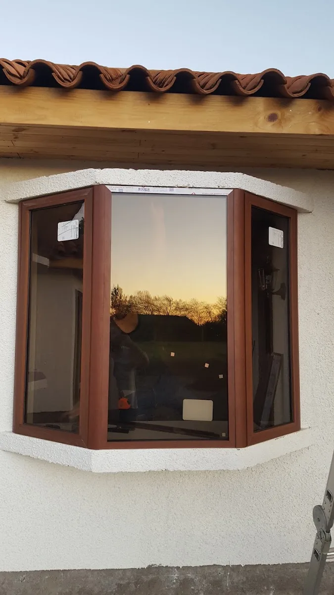 Ventana esquinera de marco color madera con el atardecer reflejado en el vidrio