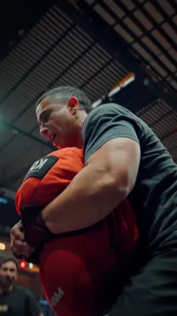 Atleta de Aria cargando sandbag en entrenamiento