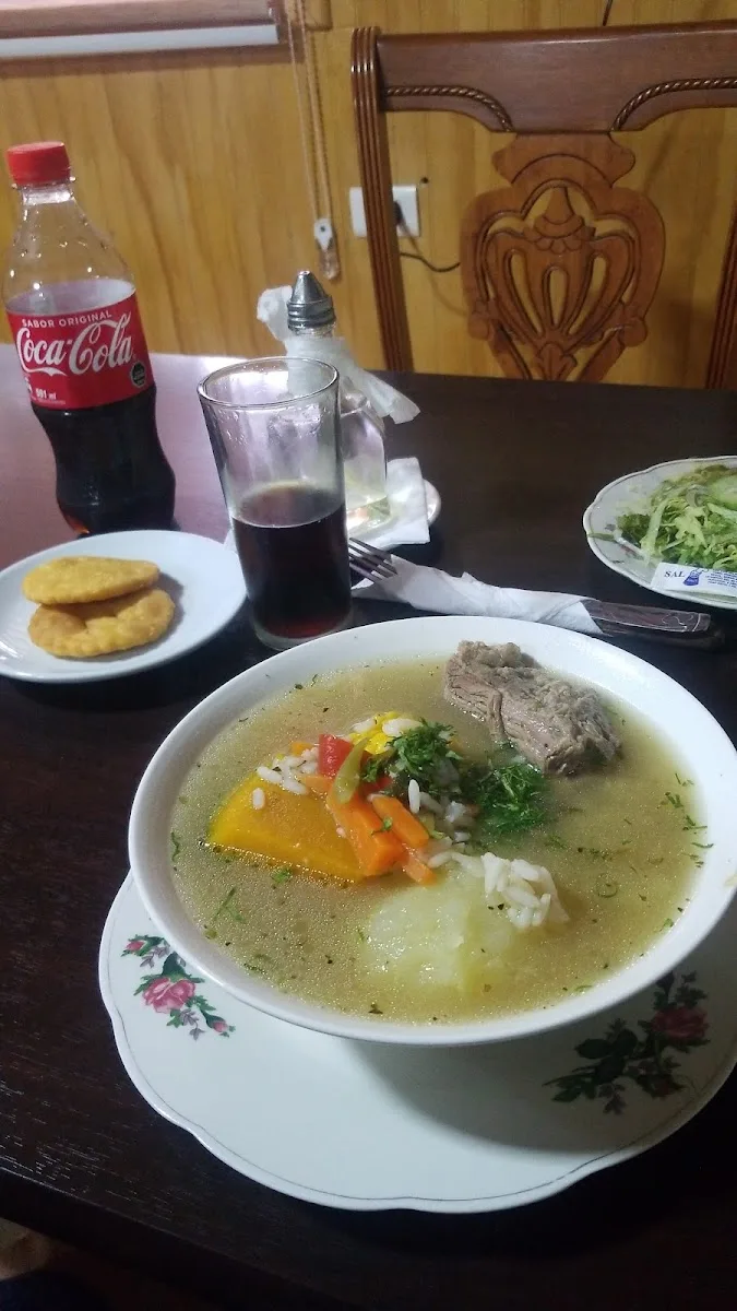 Mesa servida con cazuela, sopaipillas, ensalada y bebida