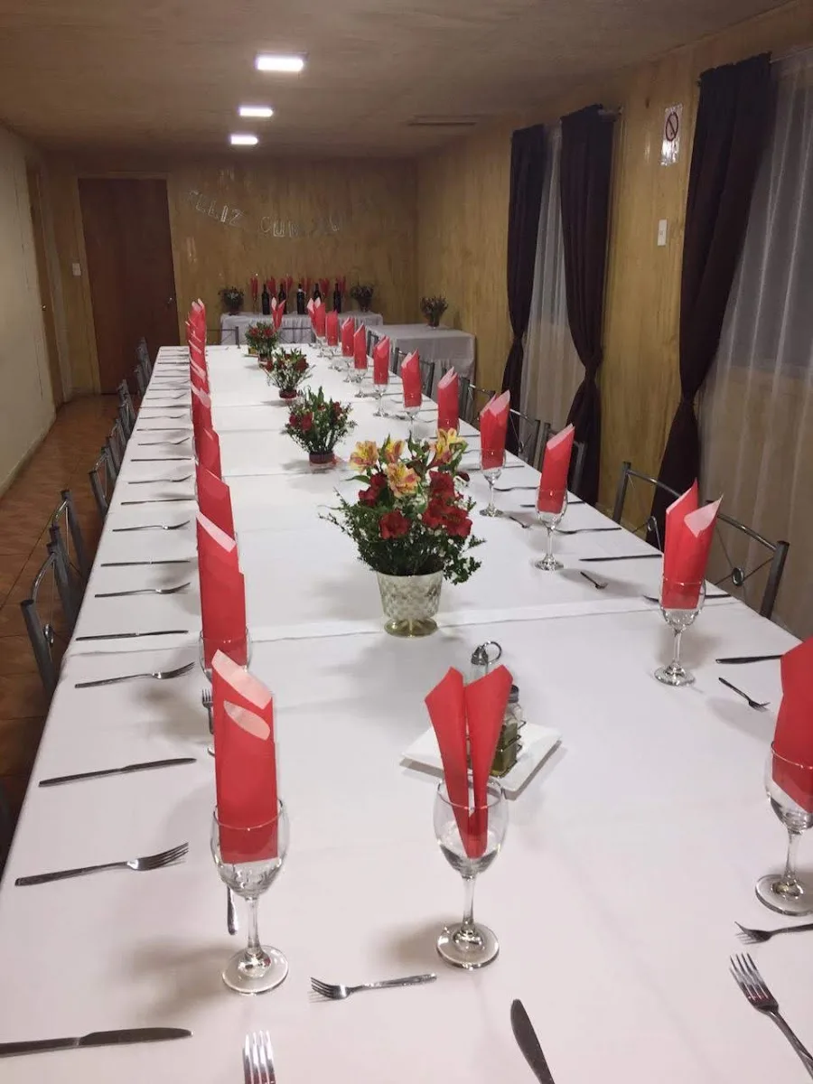 Mesa larga preparada para una celebración con servicios completos y flores