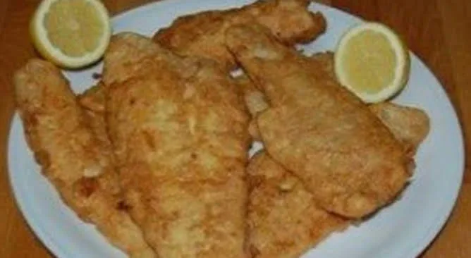 Pescado frito crocante servido con rodajas de limón