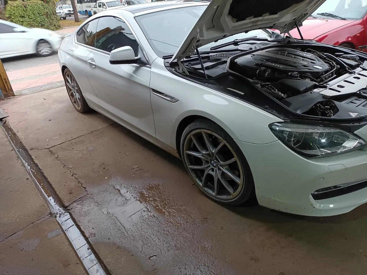 Auto blanco con el capó abierto recibiendo detailing en Autolimpio