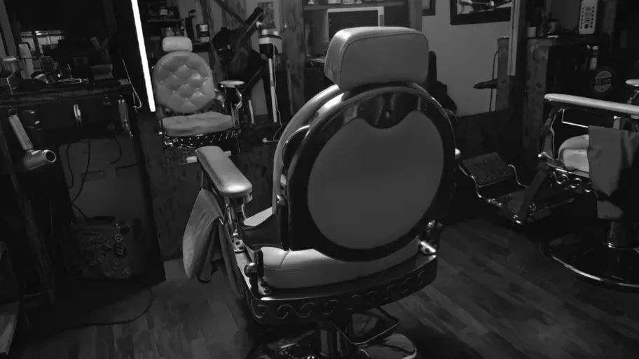 Interior de Barbería Status en blanco y negro: sillones de barbero blancos frente a los espejos