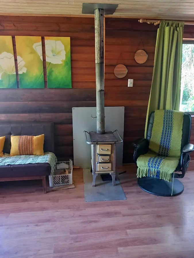 Interior de la cabaña: dormitorio con estufa a leña y madera
