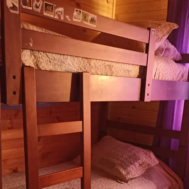 Dormitorio interior de la cabaña con camarotes de madera y ventana