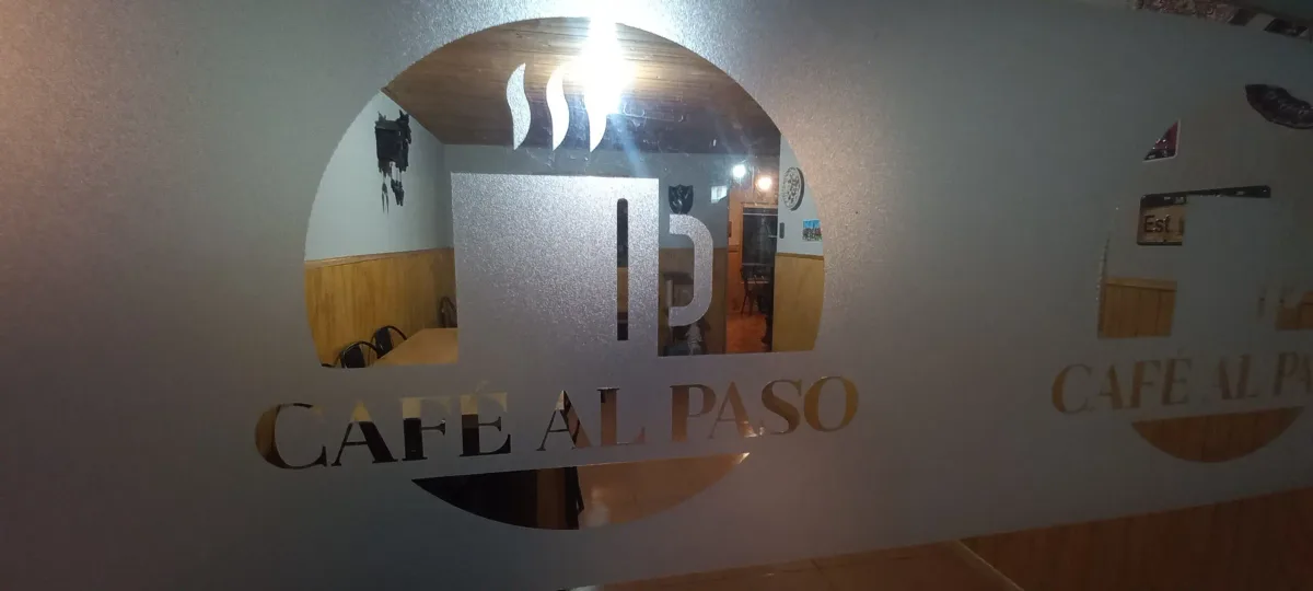 Puerta de vidrio del Café al Paso con su logo esmerilado