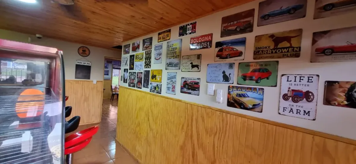 Interior del Pub La Taverna con mesas de madera, muro con cuadros y patentes decorativas
