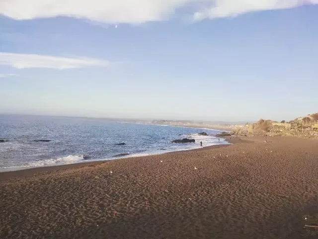 Arena oscura y mar bravío: playa para caminar — cerca de Cabañas Mar y Luz, Pelluhue