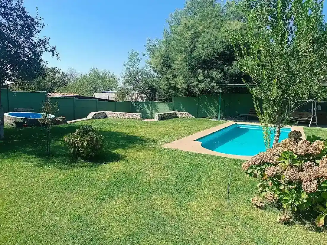 Piscina al aire libre rodeada de jardín y árboles en Cabañas Nido Verde, Talca