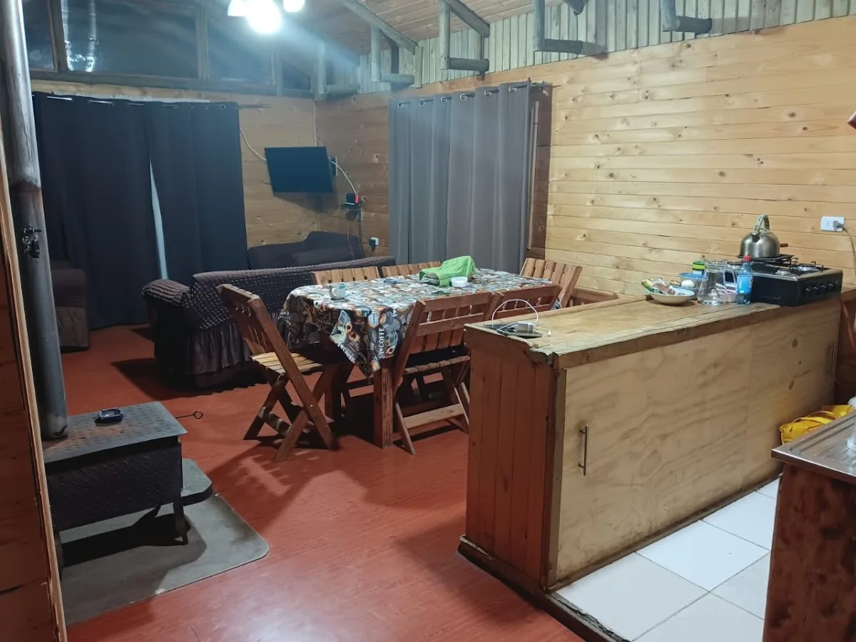 Interior de una cabaña de Cabañas Oasis: cocina, comedor de madera y estufa