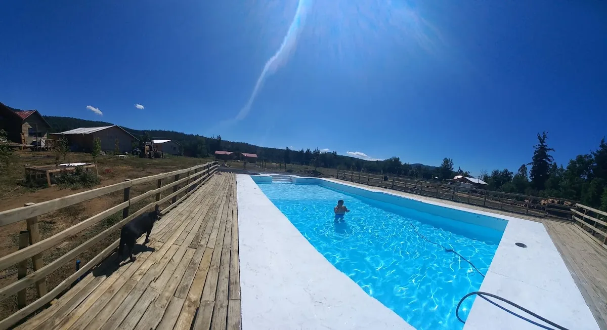 Piscina de Cabañas Oasis bordeada de madera bajo el cielo despejado