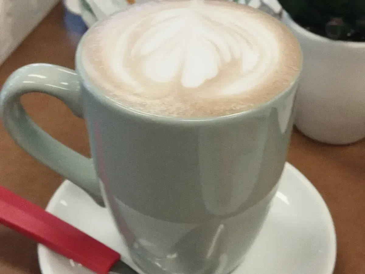 Latte art servido en la taza verde de Cactú