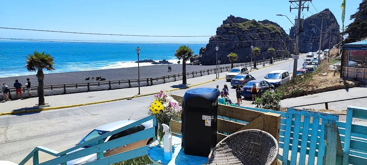 Terraza de madera de Restaurante Calypso sobre la playa, con la Piedra de la Iglesia al fondo