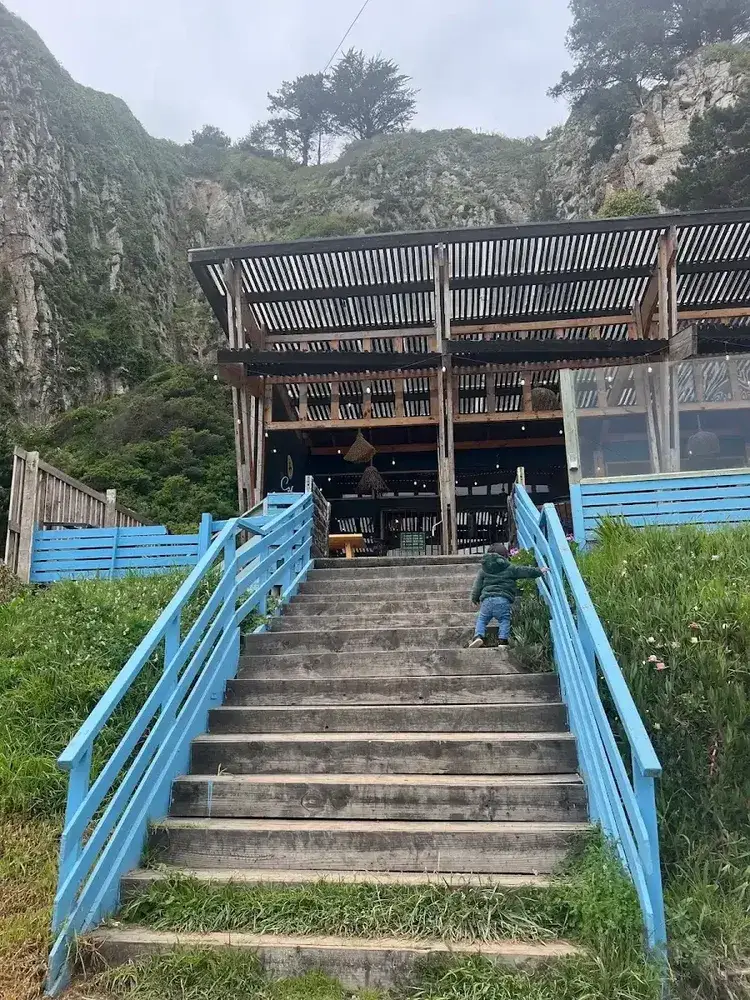 Fachada de madera de Calypso con sus escaleras azules sobre la costanera