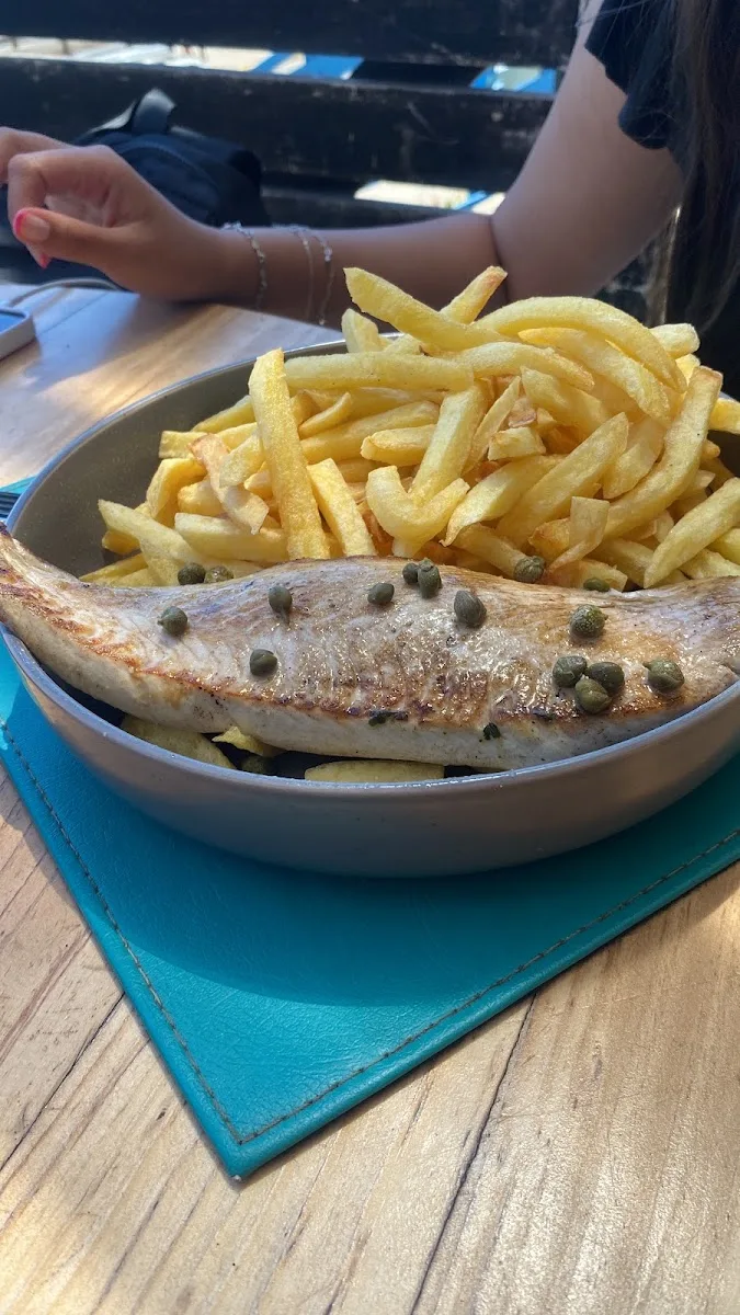 Pescado frito con papas en plato azul, especialidad de Calypso