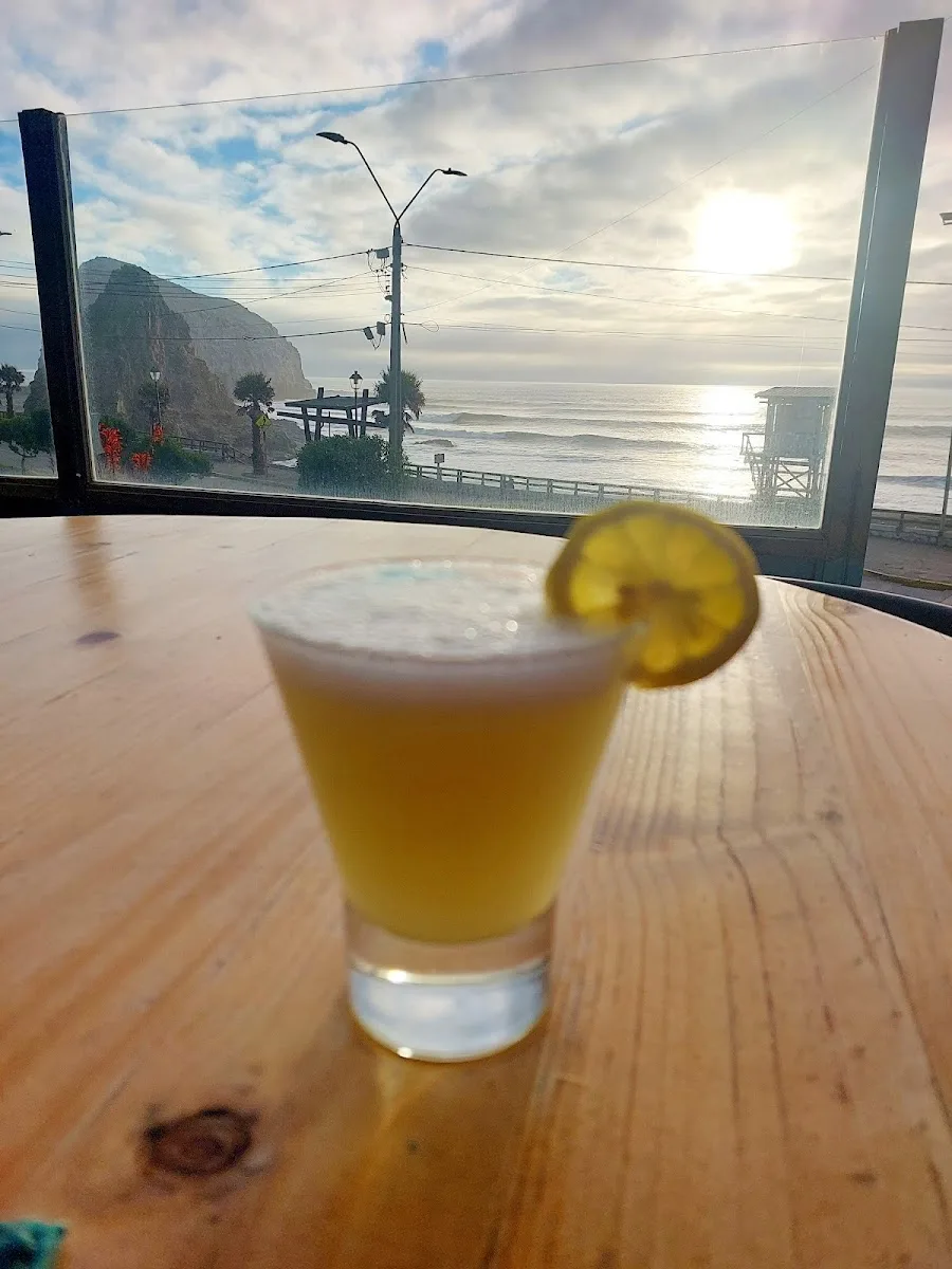 Cerveza y jugo natural sobre la mesa de Calypso con el sol cayendo sobre el mar