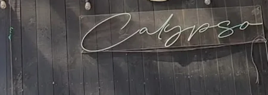 Letrero Calypso en letra cursiva sobre la pared de madera del local