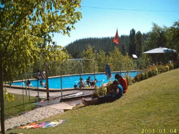 Familias descansando en el pasto junto a la piscina del camping