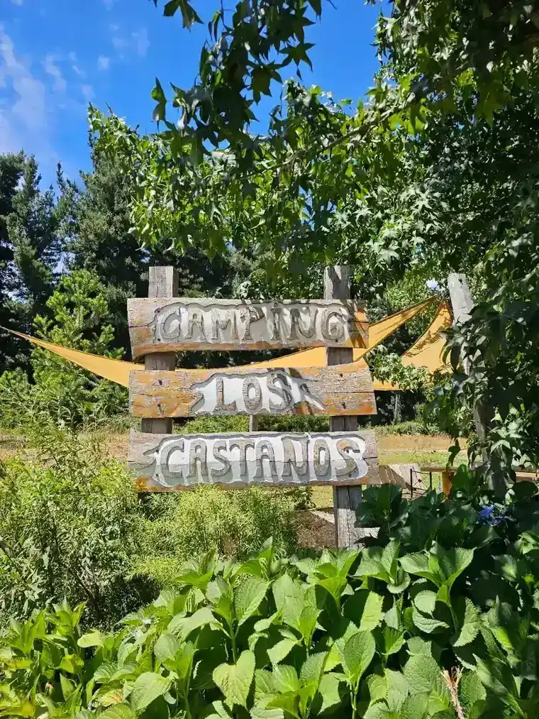 Letrero de madera pintado a mano en la entrada de Camping Los Castaños