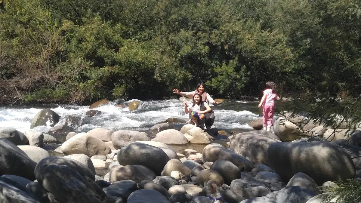 Orilla rocosa del río con personas descansando