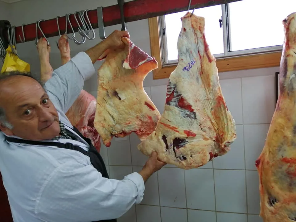 Piezas de carne colgadas en ganchos dentro de la cámara de Carnes Bravo