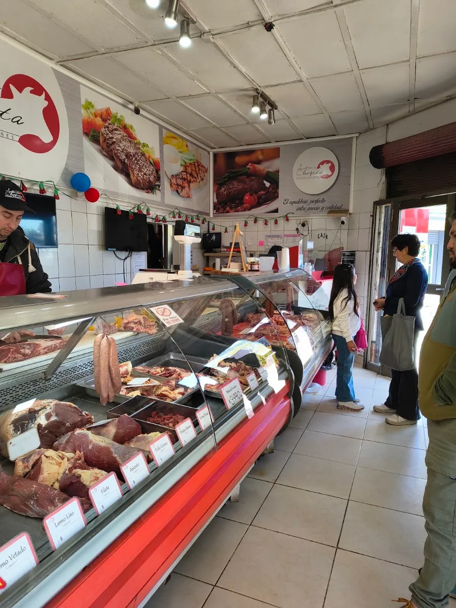 Interior de Carnicería La Chepita: vitrina roja con cortes y el logo en el muro
