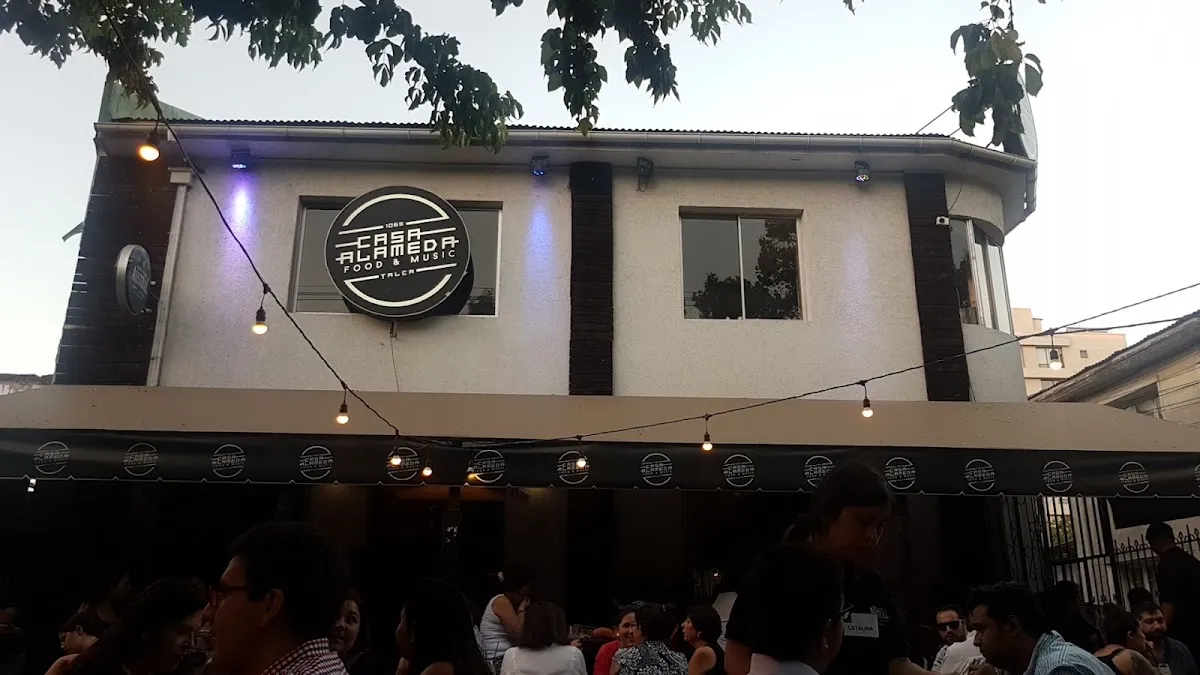 Fachada de Casa Alameda de noche con su logo circular iluminado