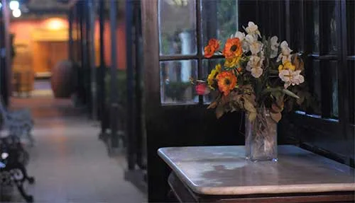 Corredor de la casona con mesa de mármol y flores frescas