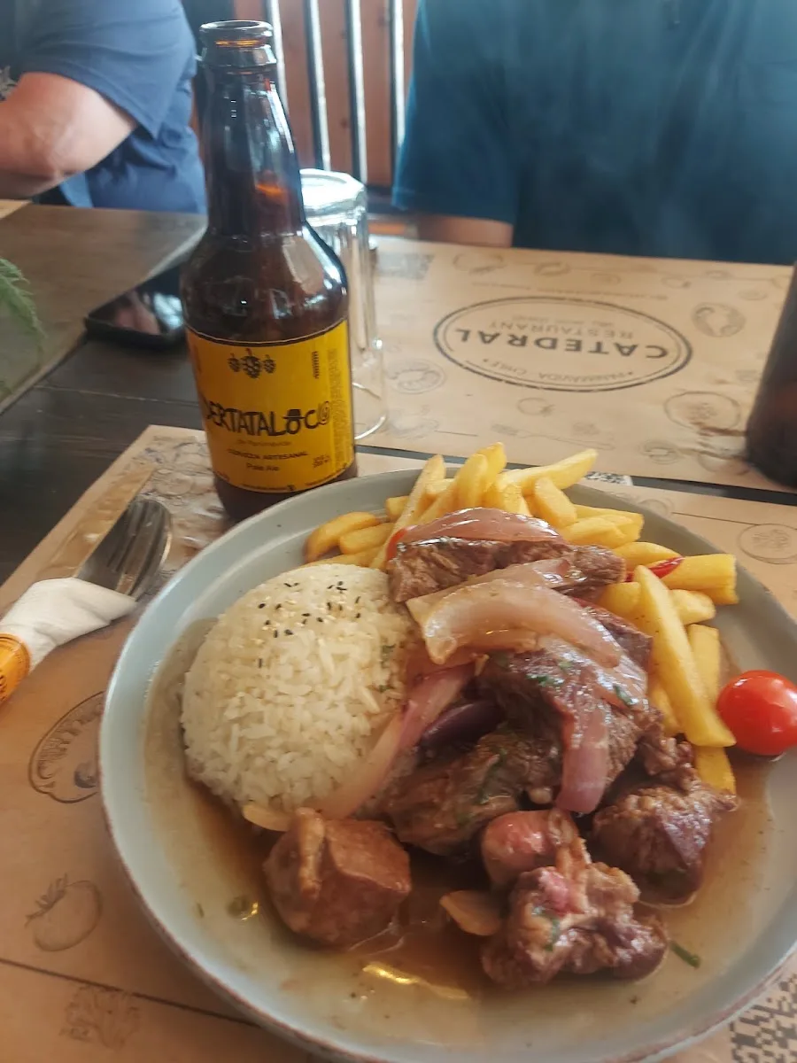 Lomo saltado con arroz y papas fritas junto a una cerveza artesanal local