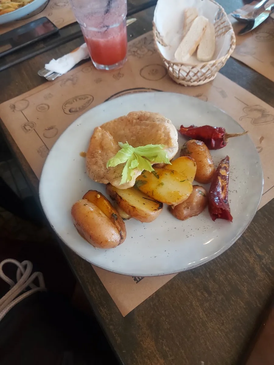Plato con papas rústicas, carne y pan sobre papel kraft con sello