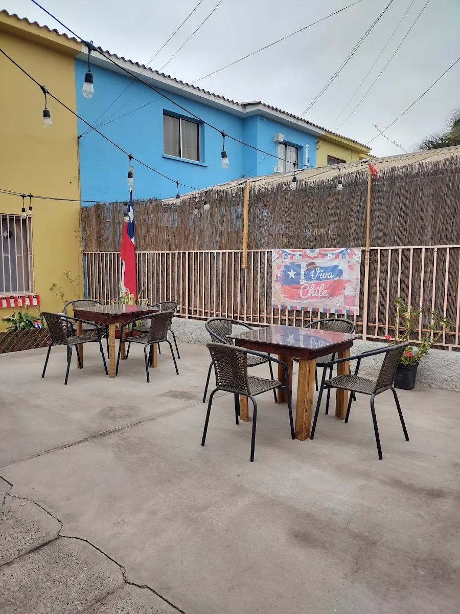 La terraza de Catffeine con mesas y sillas entre dos casas de colores en Copiapó