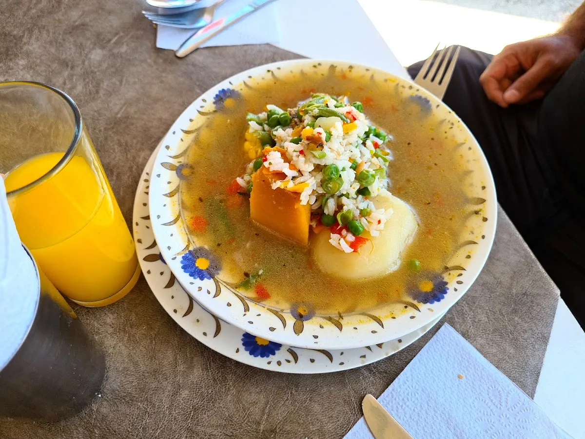 Cazuela servida con zapallo, papa, arroz y arvejas en plato de loza