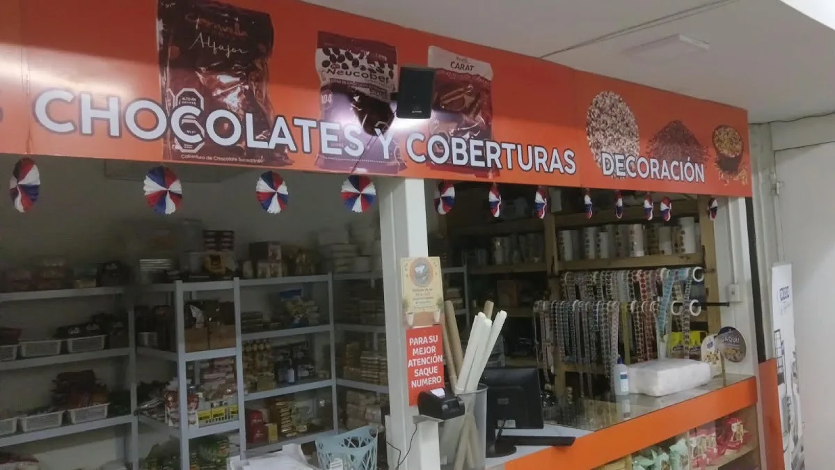 Mostrador con cartel de chocolates y coberturas sobre vitrina de productos