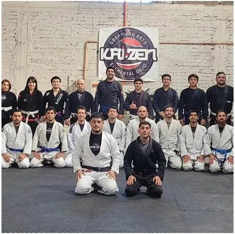 Alumnos de Kaizen con gi en el tatami, frente al lienzo del dojo