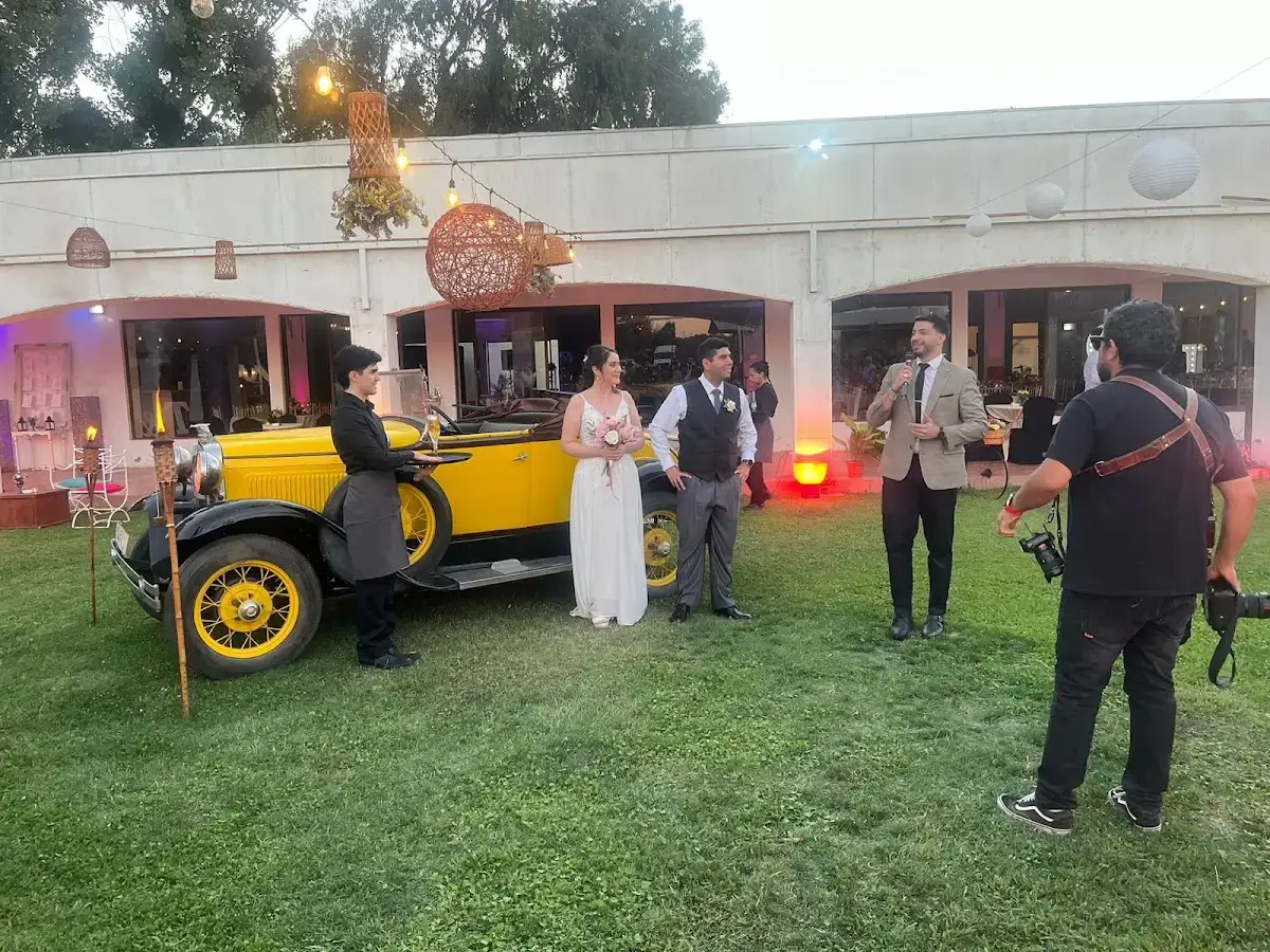 Cortejo de matrimonio posando junto a un auto antiguo amarillo