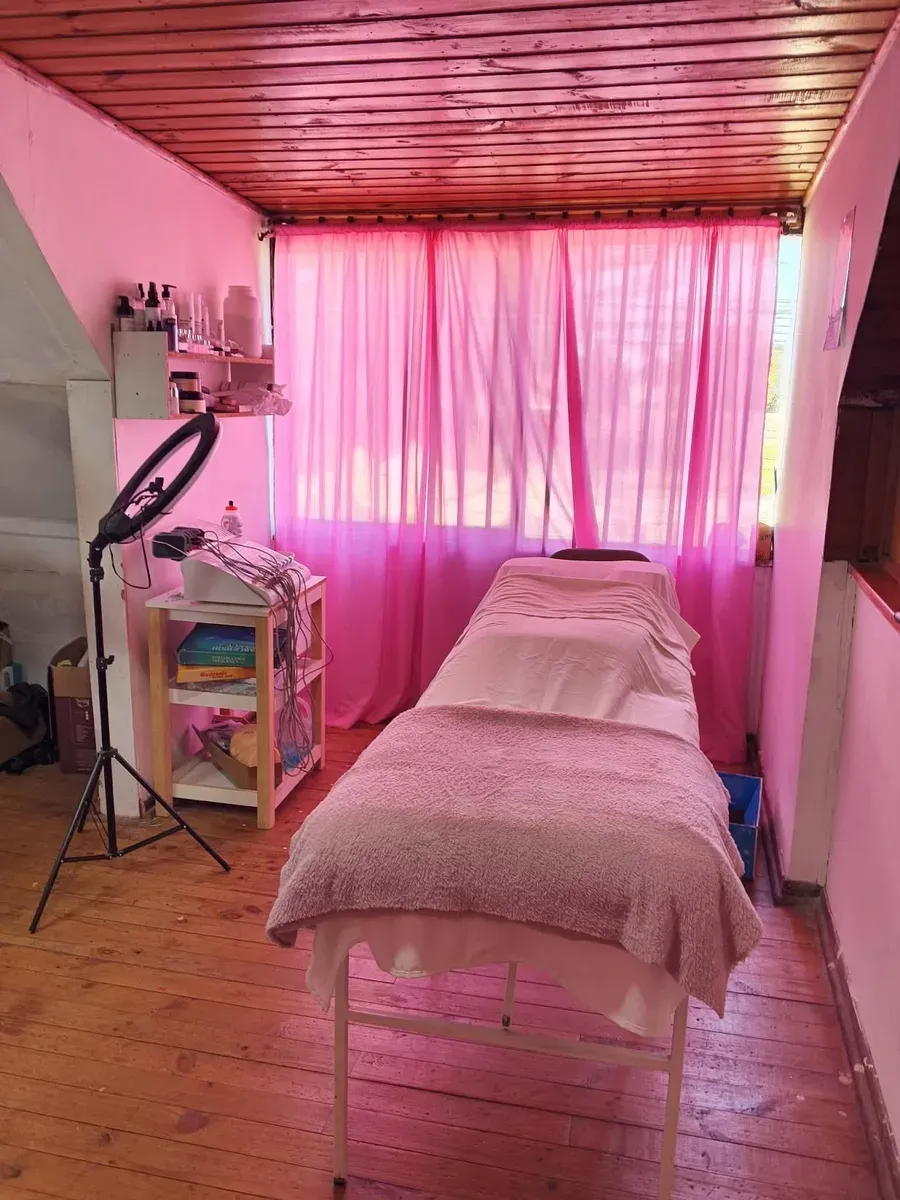 Otra cabina rosada del salón con camilla y aro de luz