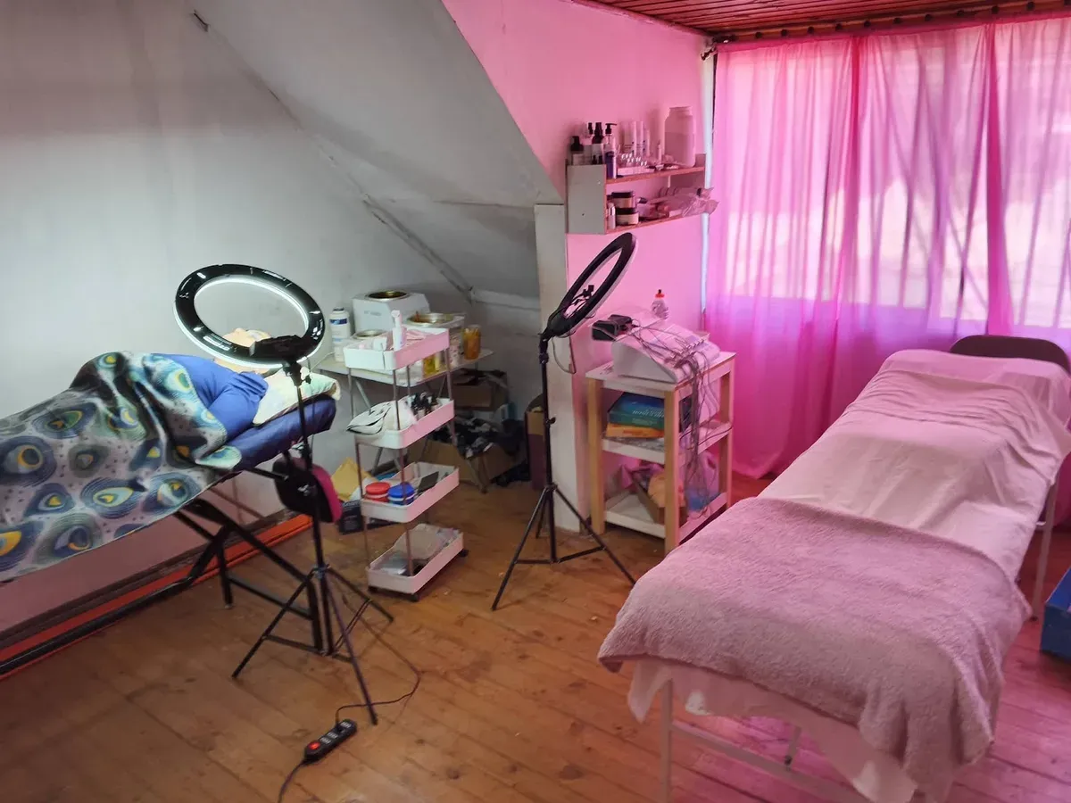 Cabina de masajes con camilla rosada e iluminación cálida en CG Salón Spa