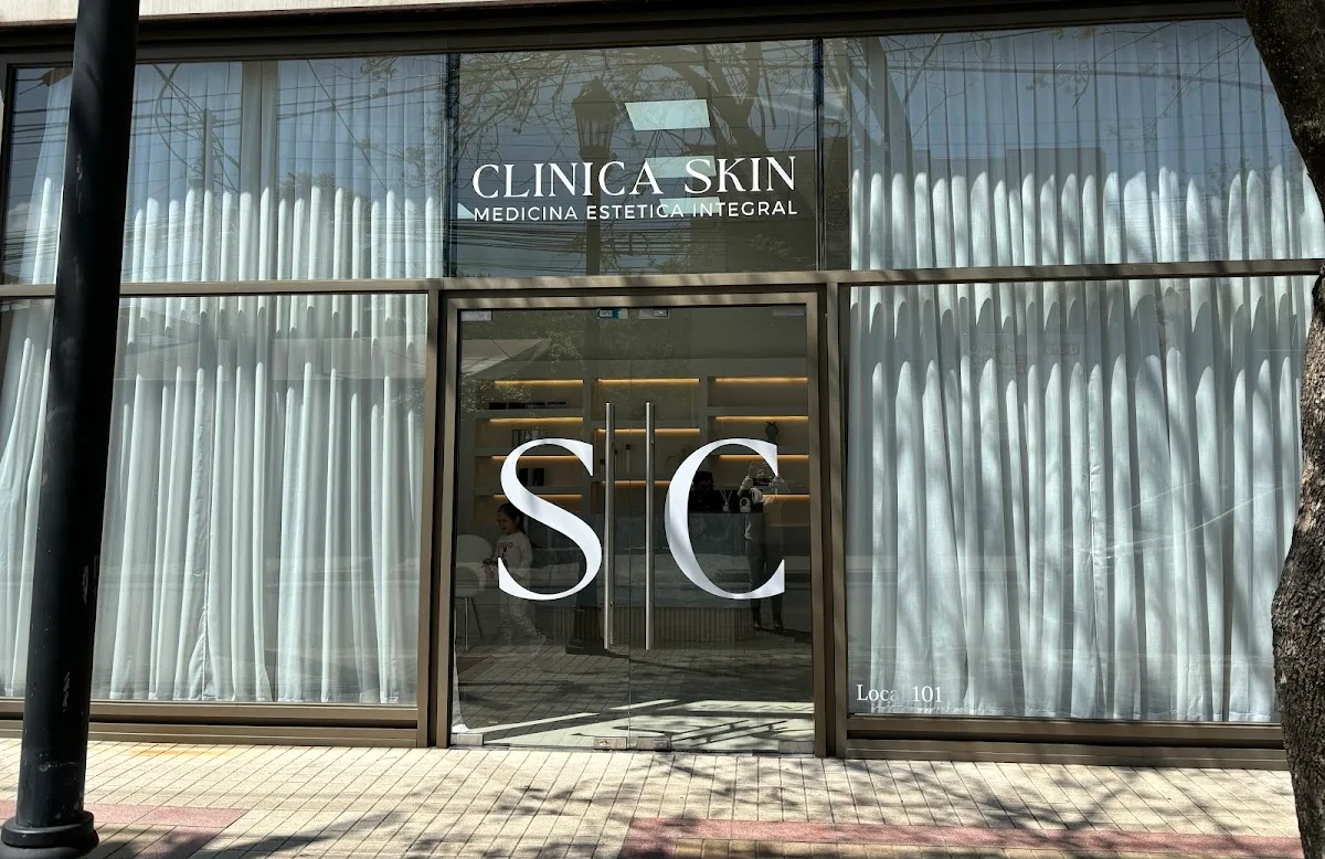 Fachada de vidrio de Clínica Skin en Calle 1 Poniente: cortinas claras y el monograma SC en la puerta