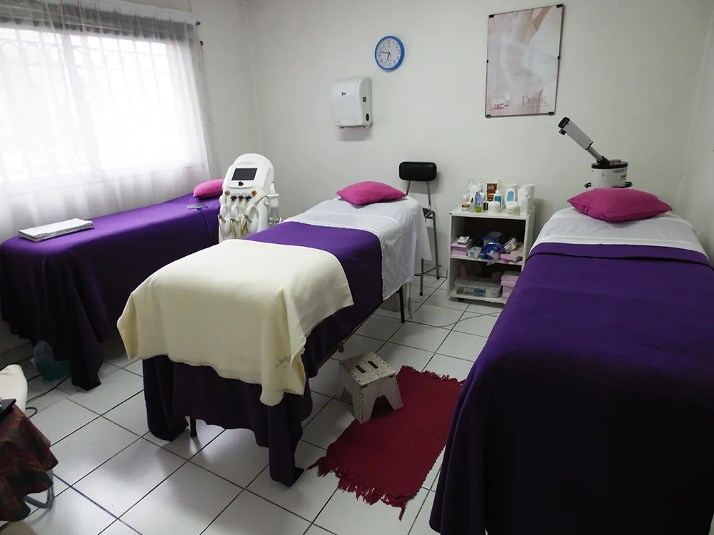Sala de masajes de Clínica Skin con camillas violetas y luz baja
