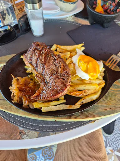 Filete a la plancha con papas fritas y huevo frito, servido en sartén de fierro