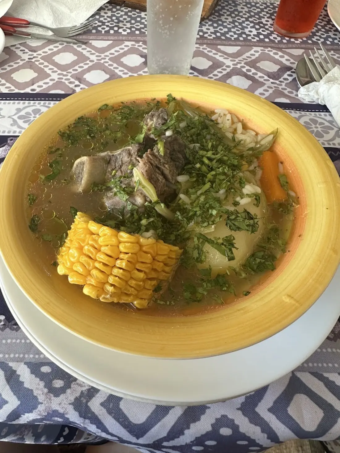 Cazuela humeante con choclo y carne servida sobre mantel a cuadros
