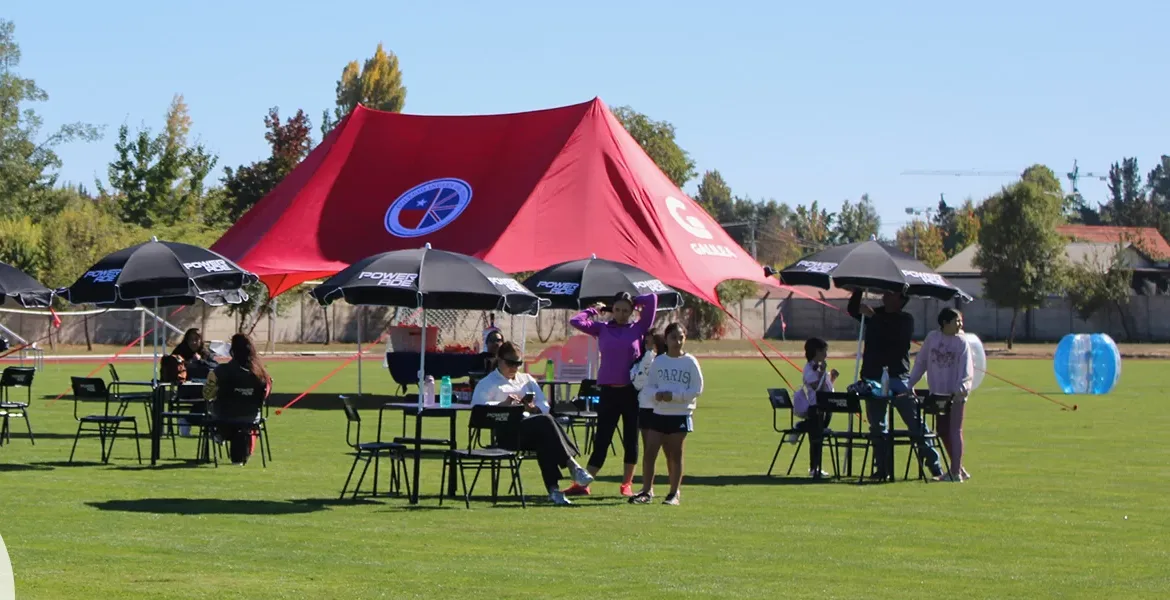 Carpa roja del colegio en la cancha de pasto del campus en una jornada deportiva