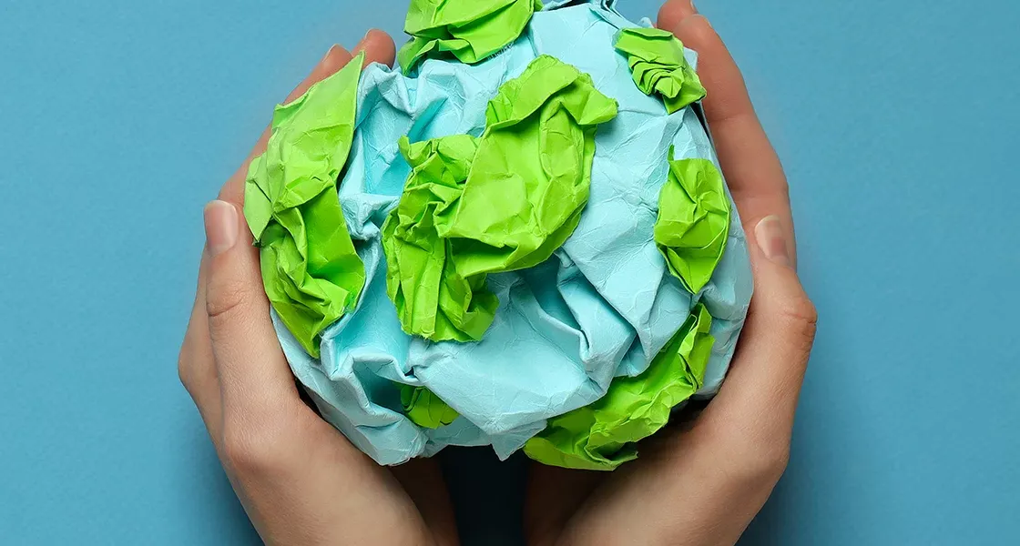 Manos sosteniendo un planeta hecho de papel por estudiantes