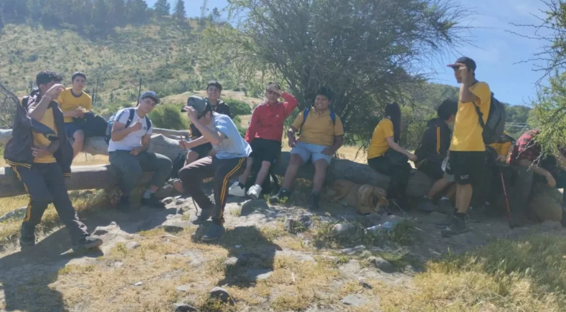 Salida pedagógica de III medio: estudiantes con poleras amarillas del colegio caminando por un sendero de cerro
